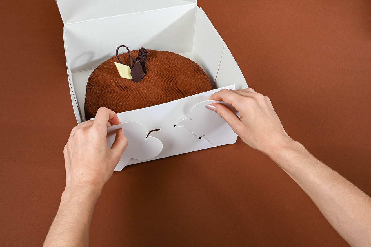 Der Kuchenkarton mit anhängendem Deckel ist einfach aufzurichten.