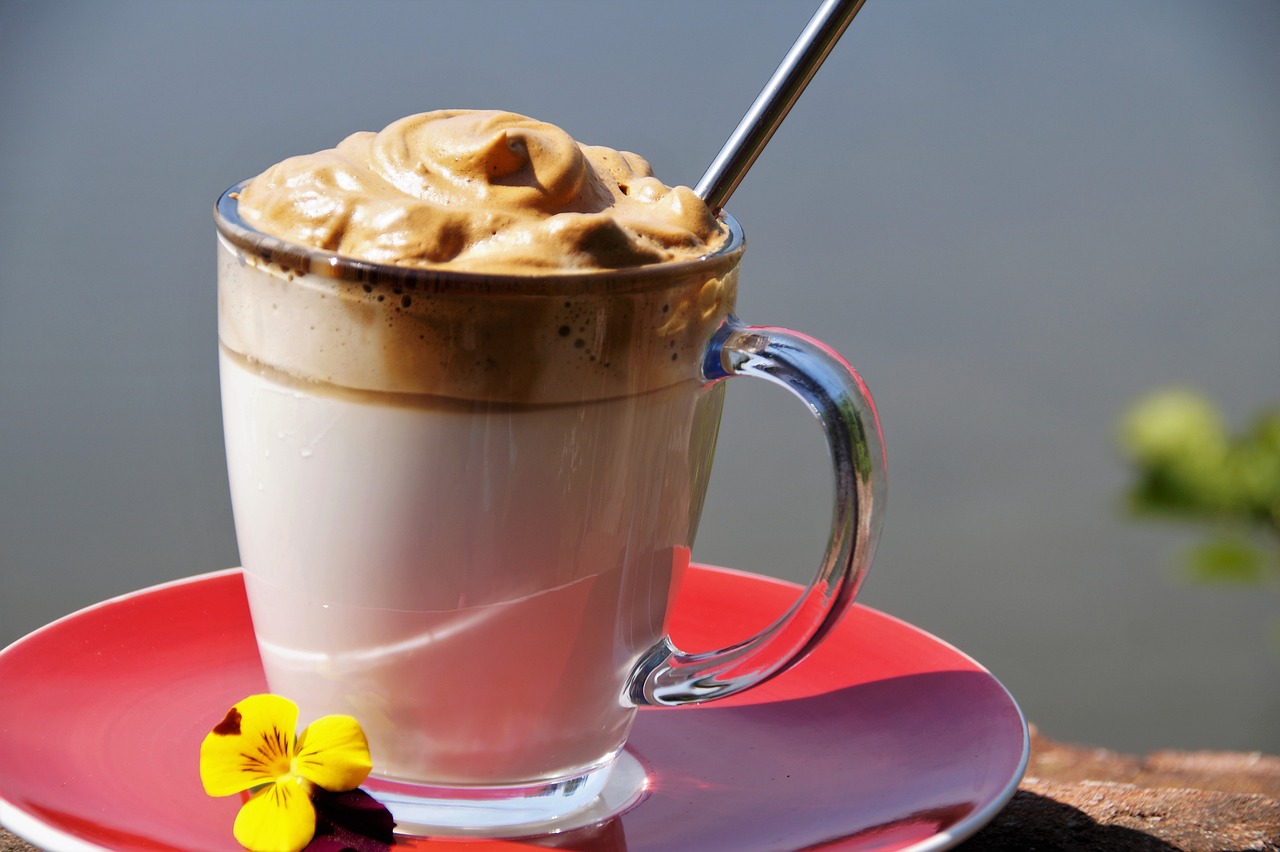 Dalgona Kaffee, im Glas, Strohhalm, rote Untertasse