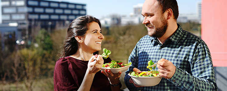 2 Personen essen Salat aus To-go-Verpackung