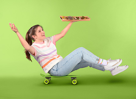 Une dame roule sur un skateboard avec un plateau de restauration à la main.