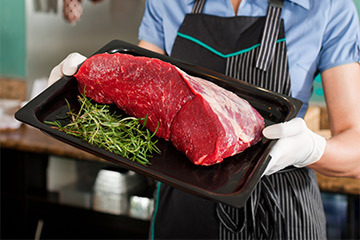 Metzgereifachverkäufering mit einem Stück Rindfleisch Metzgereifachverkäufering mit einem Stück Rindfleisch