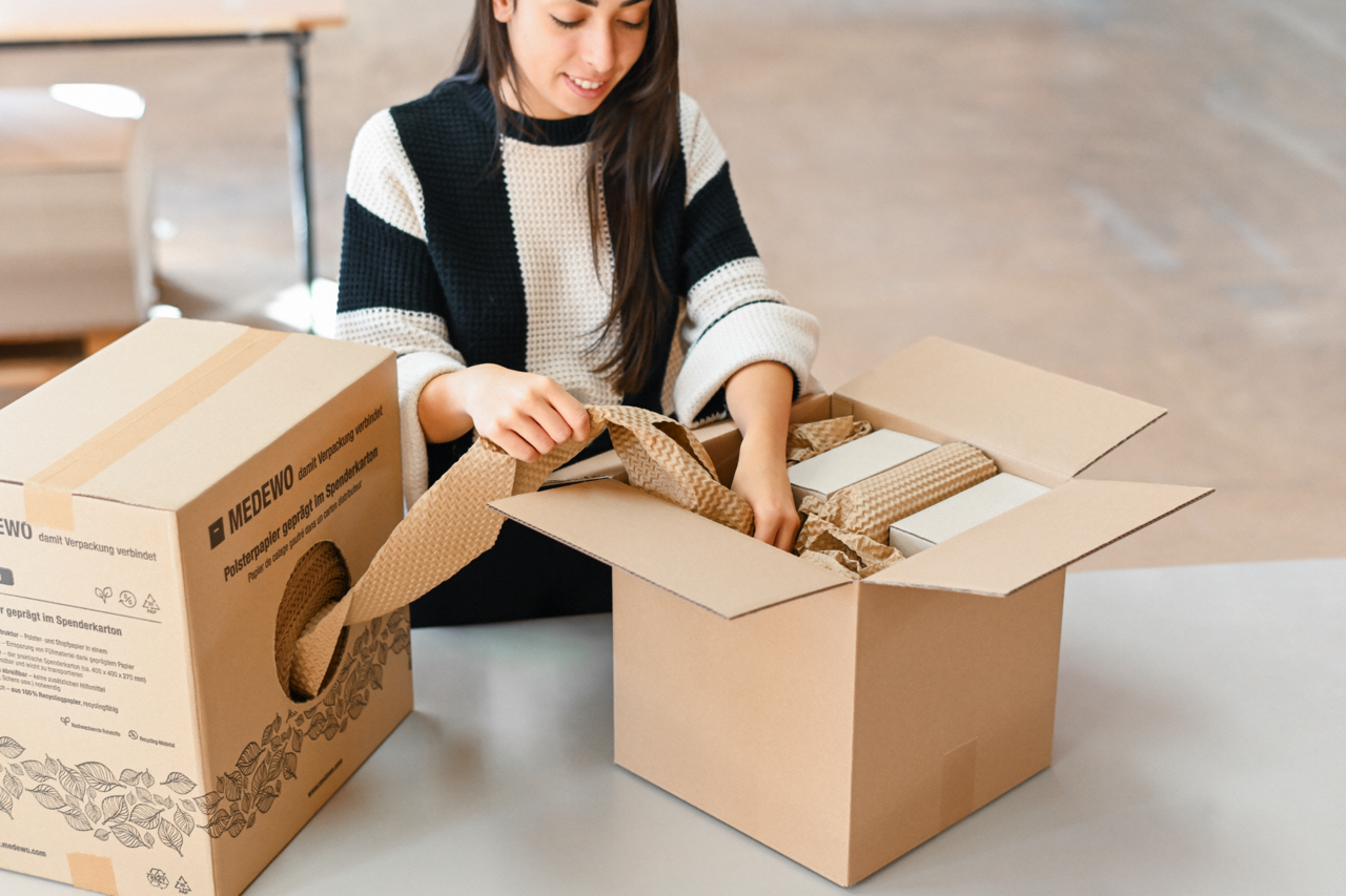 Spenderkarton mit Stopfmaterial ist mobil am oder auf dem Packtisch einsetzbar