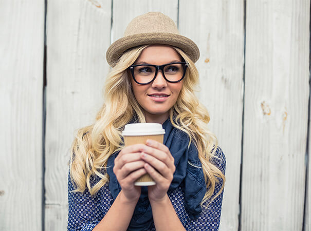 blonde Frau mit Kaffeebecher in der Hand