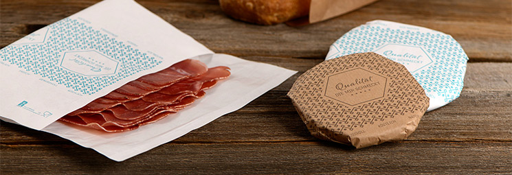 Metzgerpapier mit Wurstwaren auf Holztisch Metzgerpapier mit Wurstwaren auf Holztisch