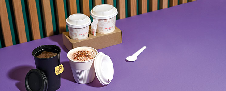 verschiedene Kaffeebecher mit Deckel, Löffel und Zuckersticks