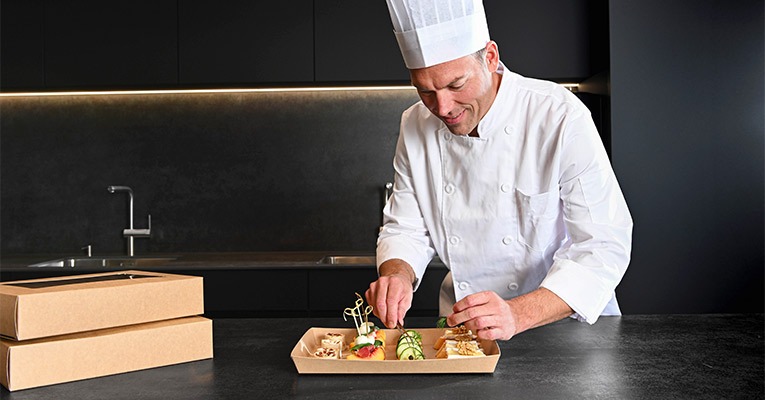 Zur unseren Verpackungen für Ihr Catering → Koch richtet Essen für Catering an
